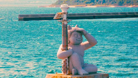 Stone cat statue guarding a small harbor beacon along the Seto Inland Sea