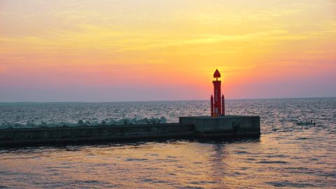 Red harbor beacon silhouetted against a golden Seto Inland Sea sunset